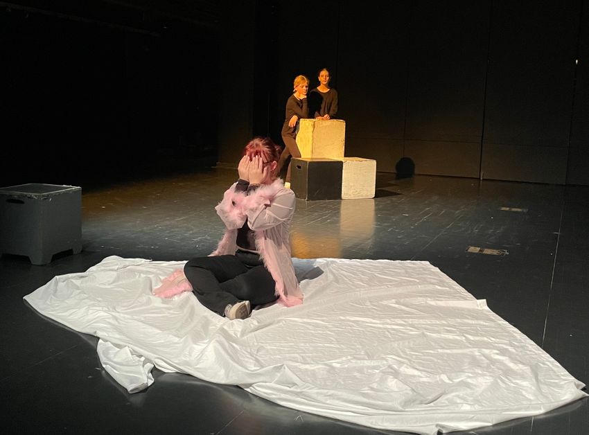 A student actress sprawled out on a blanket on stage delivering their lines